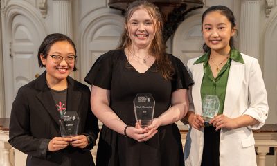 photo of three young women smiling and holding trophies.