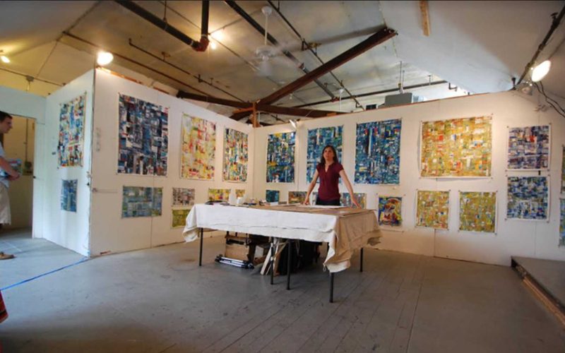 Person standing at a table in a gallery at Central St. Studios in Somerville