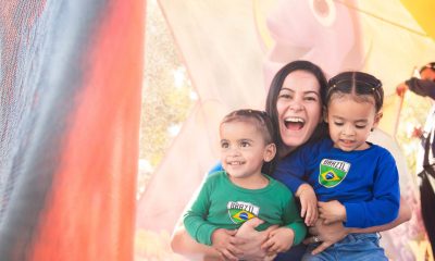 photo of a woman smiling widely and holding two children who are also smiling.
