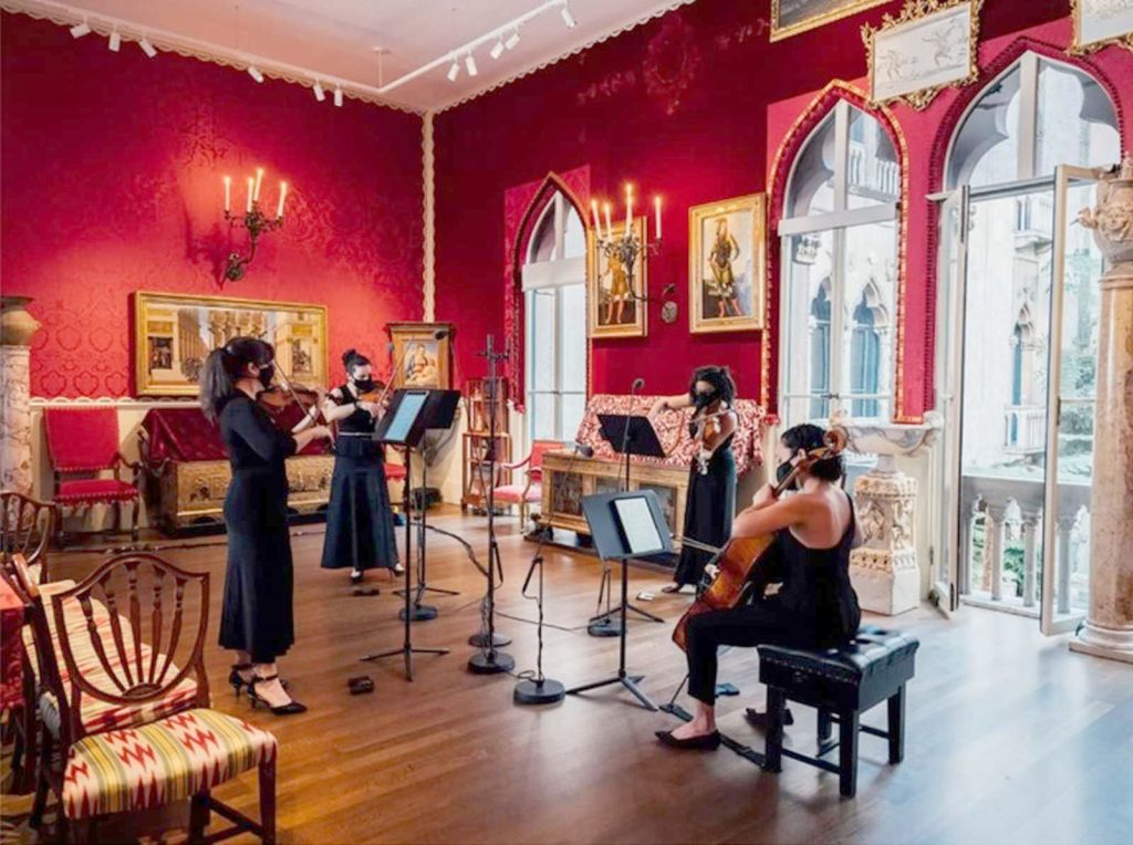 photo of a string quartet giving performance in an ornate room with red walls at the Isabella Stewart Gardner Museum.