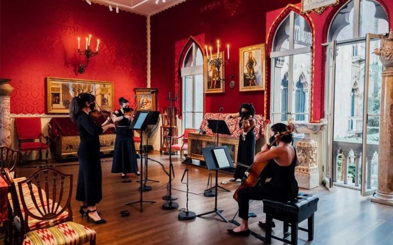 Four composers giving a musical performance in an ornate room with red walls at the Isabella Stewart Gardner Museum