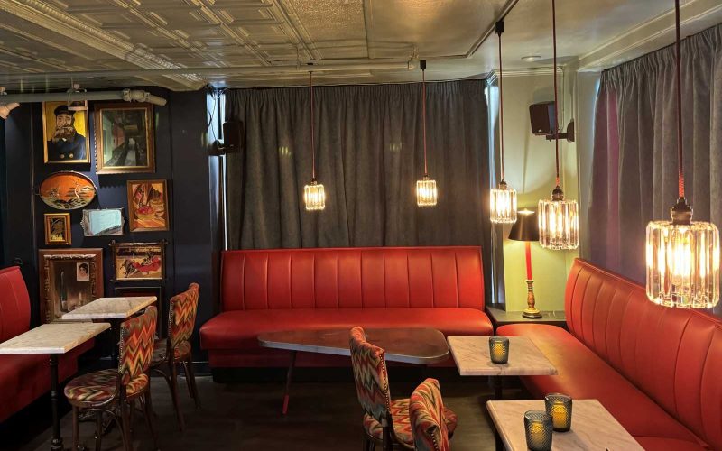 Lounge areas with tables and red cushioned benches at Images Cinema