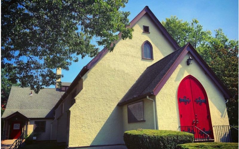 Yellow stucco from exterior with a bright red front door to the Drama Studio