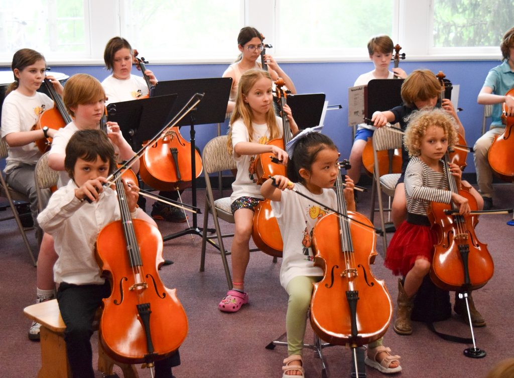 photo of about a dozen little kids playing their cellos.