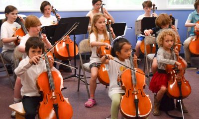 photo of about a dozen little kids playing their cellos.