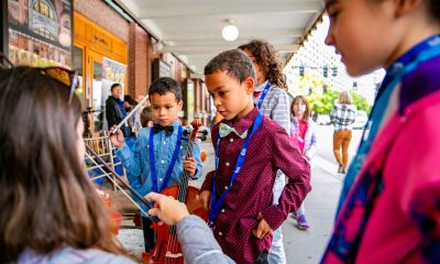 photo of kids watching a woman showing them how to hold a violin bow.