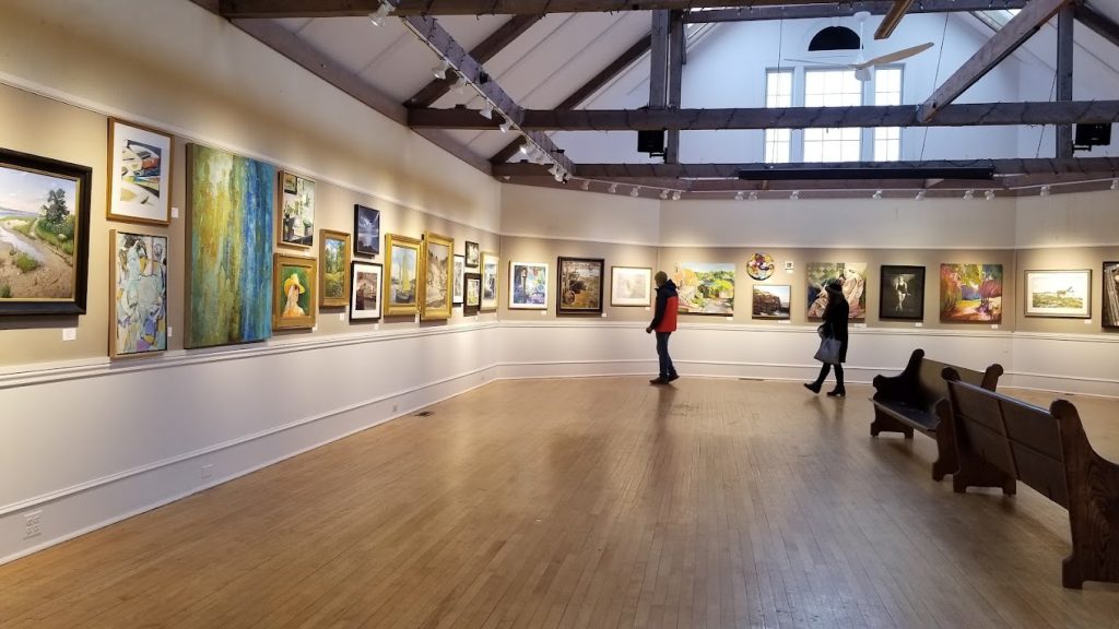 People viewing art hanging in a gallery.