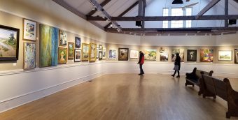 People viewing art hanging in a gallery.