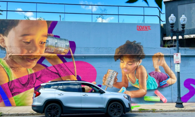 mural depicting 2 young boys holding tin cans connected by string to their ears. One is also drawing with sidewalk chalk in his free hand.