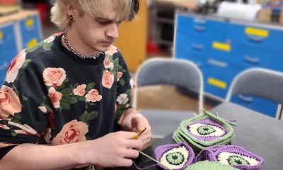 photo of a knitter working on a series of pieces that look like eyes.