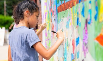 photo of a child drawing on an outdoor mural.