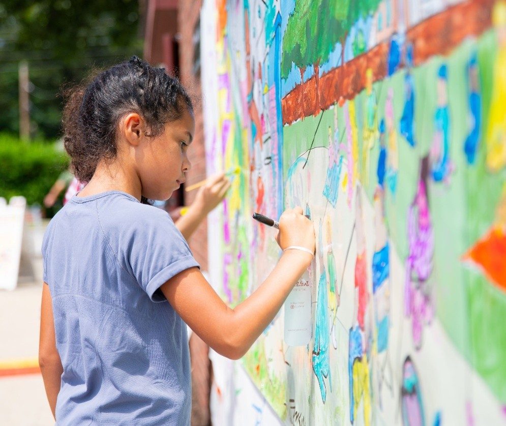 photo of a child working on an outdoor mural.