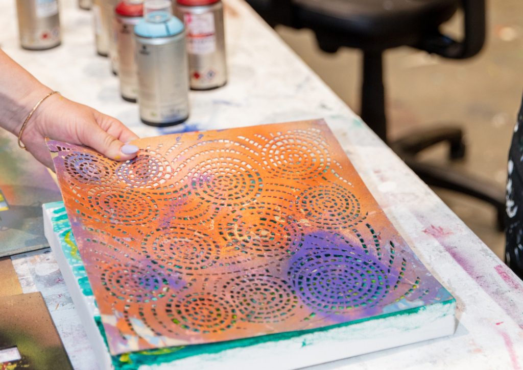 photo of an artist spray painting a stencil