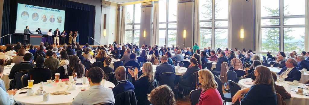 photo of a large room full of seated people facing a stage where a panel of people are getting an award.