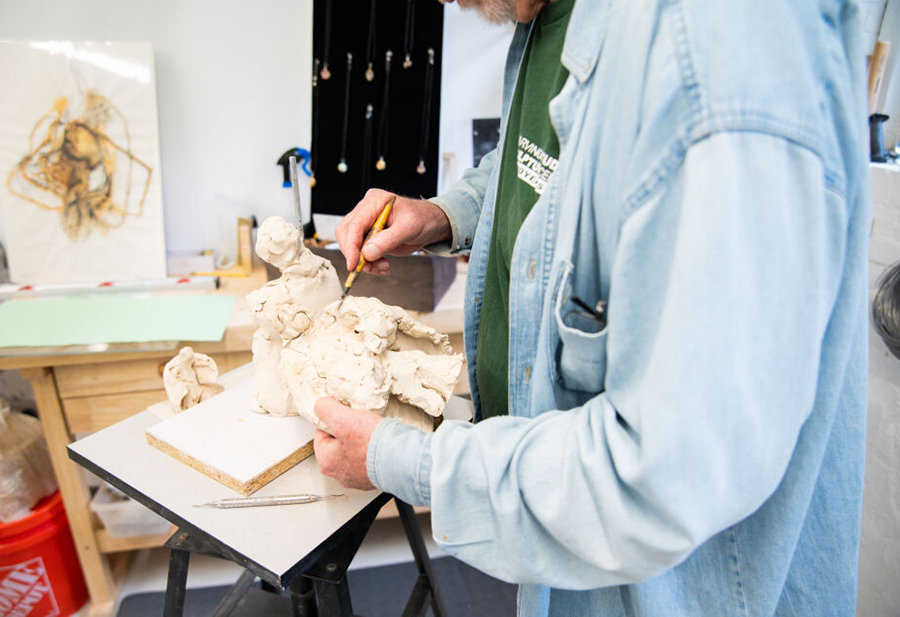 photo of an artist working with clay in his studio.