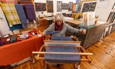 photo of a fiber artist seated at the loom working.