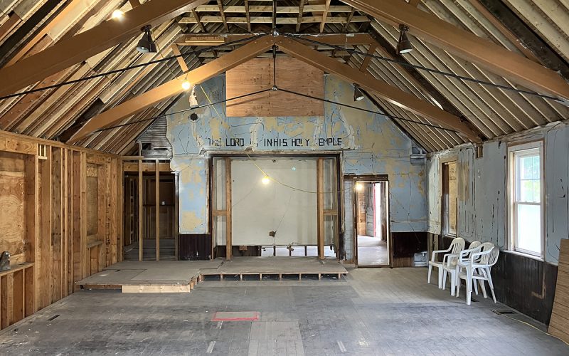 The interior of a former church building stripped down to pine wood beams and subfloors