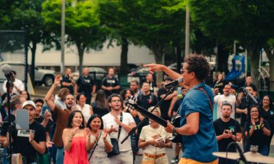 photo of a crowd dancing and clapping to a live music performance in a park.
