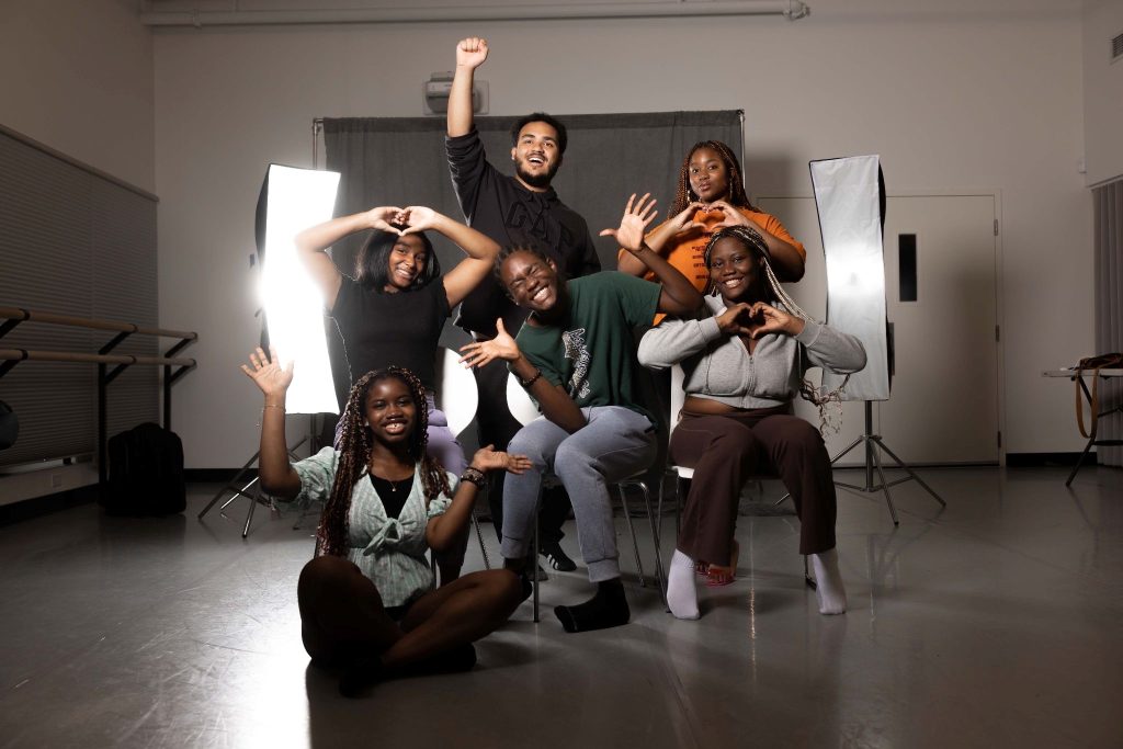 photo of half a dozen young people making happy gestures with their arms and faces.