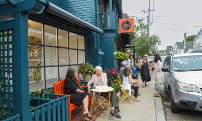 photo of a bustling street - people are sitting outside an art gallery while other are talking in groups in the background.