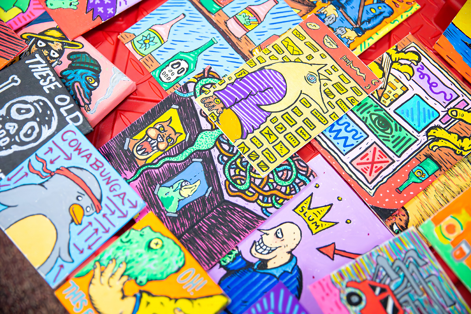 close up photo of a table covered with various bright illustrations and works on paper for sale at an open studio event.