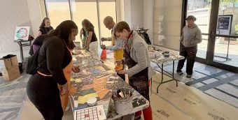 photo of people in aprons painting a long canvas.