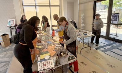 photo of people in aprons painting a long canvas.