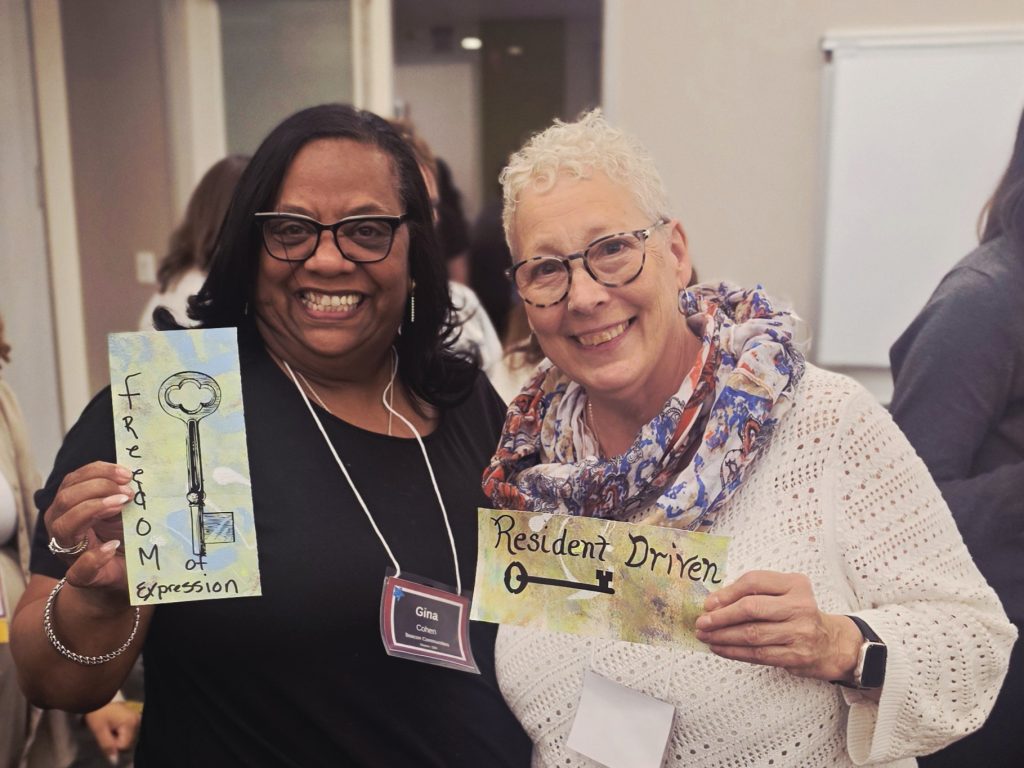 two women sharing their contributions to a collage project.