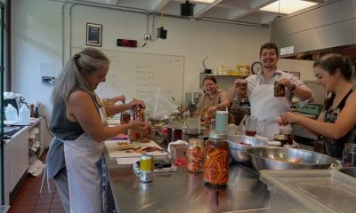 photo of a commercial kitchen with people wearing aprons and pickling carrots.