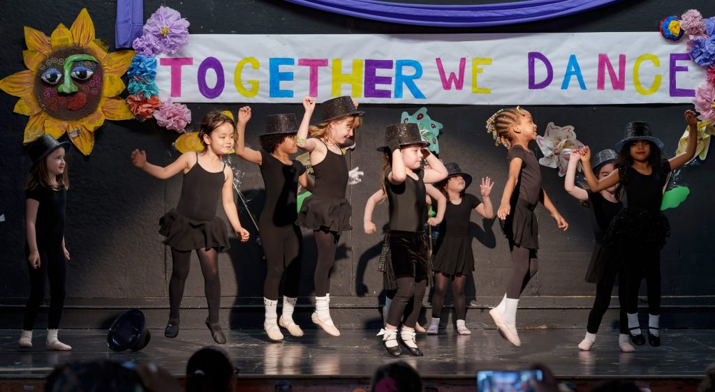 photo of a dozen young dancers performing under a banner that says together we dance.