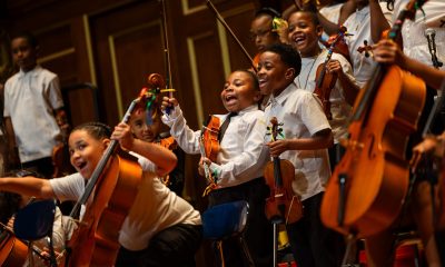 a group of young musicians laughing, holding their stringed instruments in between performing.