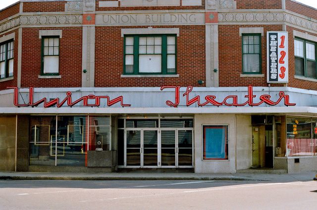 photo of a façade of a historic brick building with the inscription "Union Building" at the top, a row of windows, and a vintage marquee reading "Union Theatre" above four double-doors at the street level.