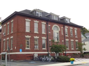 photo of a three-story brick building with bicycles parked by the entrance.